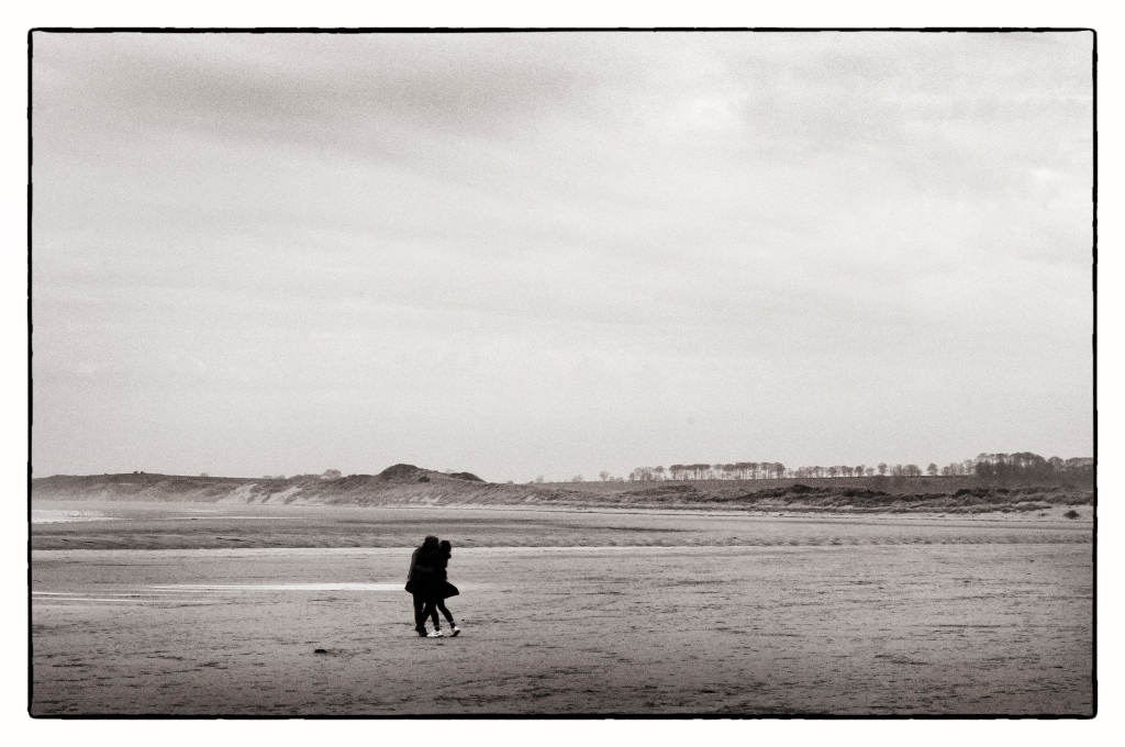 A couple embrace on Alnmouth Beach, Northumberland, UK - April 2023